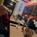 Eine Gruppe von Menschen sitzt an einem Tisch in einem Restaurant während einer Besprechung.